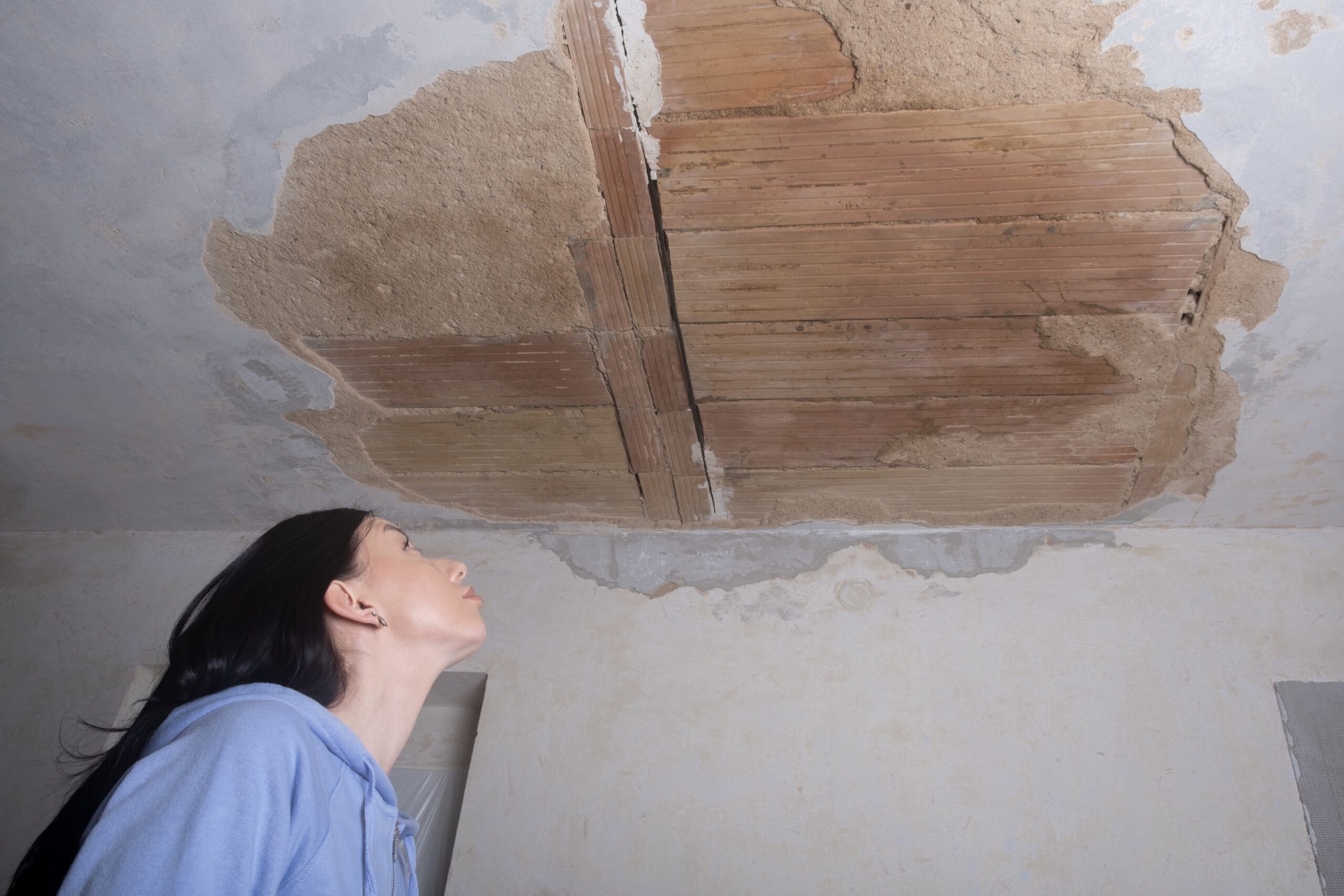 A,Young,Woman,Looking,Up,At,A,Ruined,Hole,In
