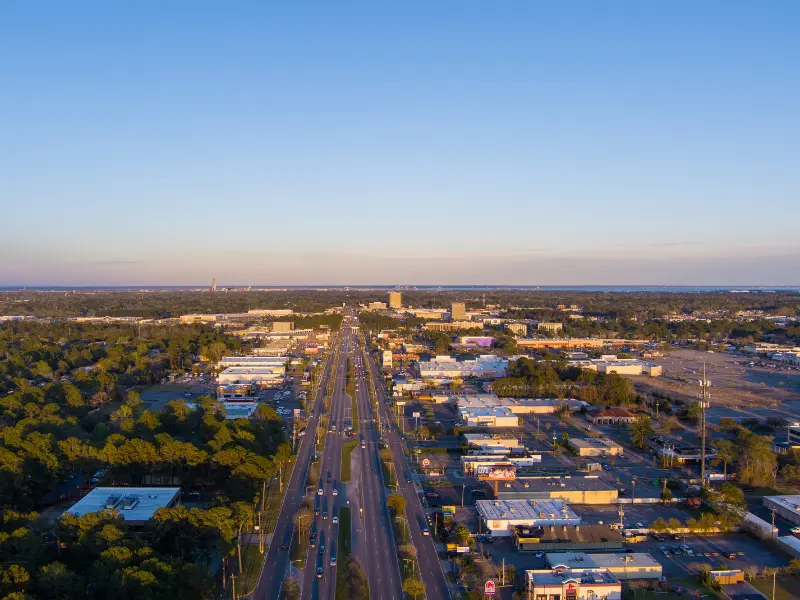 Aerial view of a highway running through a city with buildings and trees on either side under a clear sky. water damage restoration in Athens AL