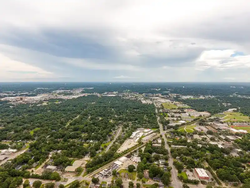 Aerial view of a suburban area with dense trees and scattered buildings under a cloudy sky. water damage restoration in Hazel Green AL